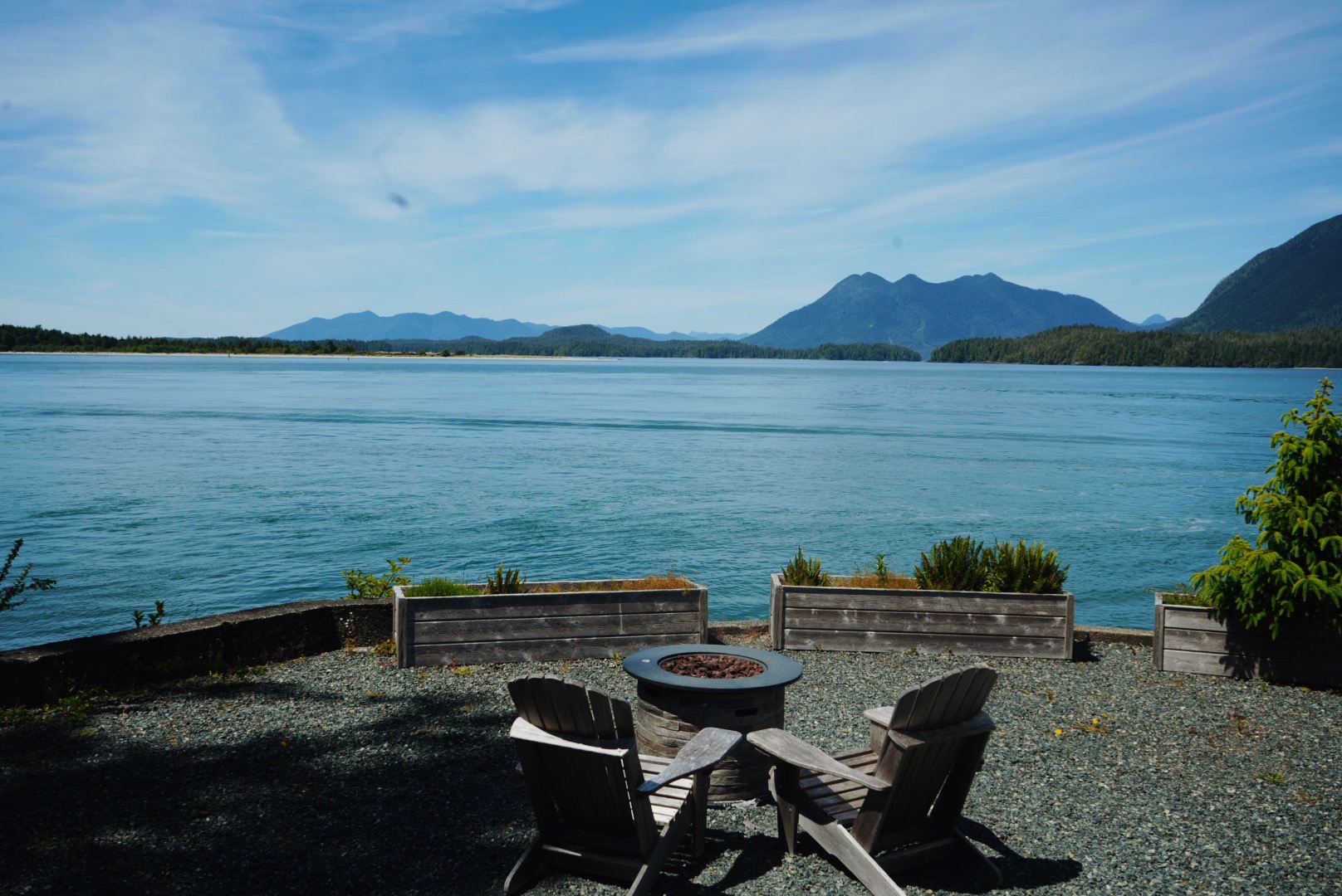 Adirondack chairs around a fire pit overlooking the water